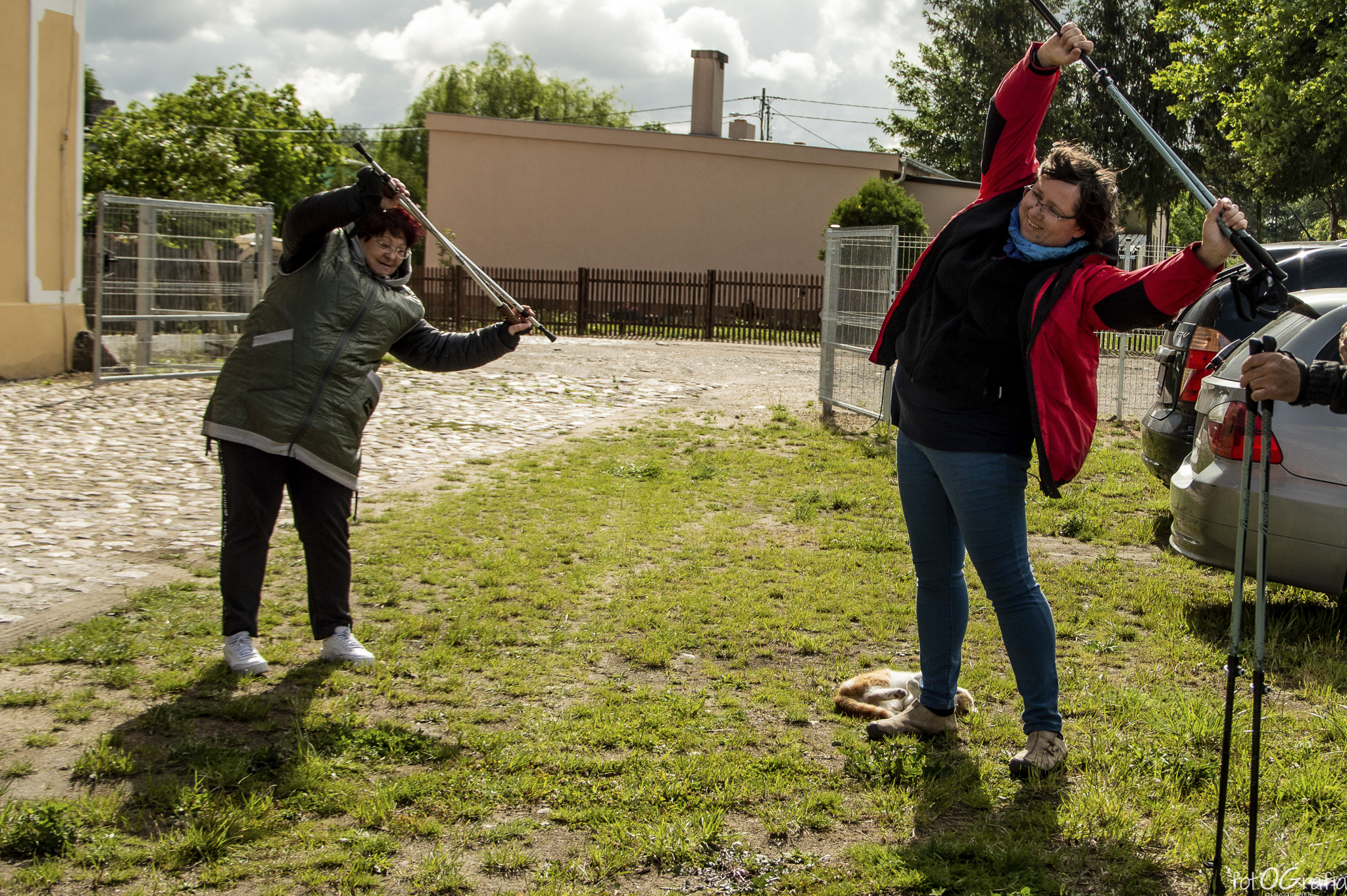 Zdjęcie przedstawia grupę ludzi biorcą udział ćwiczeniach z kijkami.