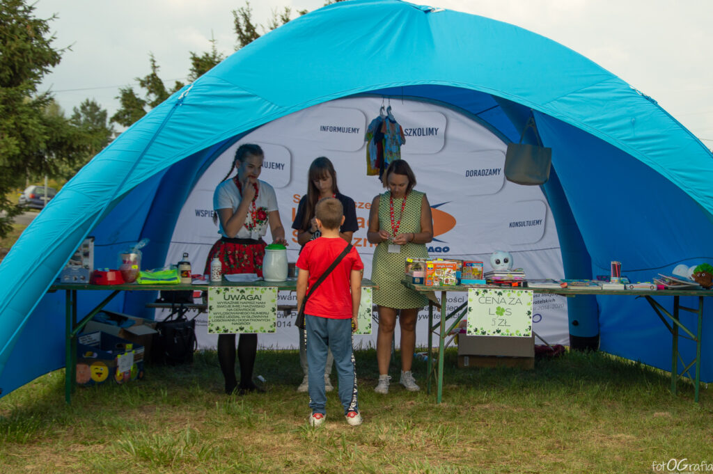 Zdjęcie przedstawia grupę kobiety pod namiotem sprzedające losy.